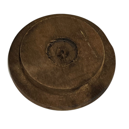 A round, dark brown wooden object with concentric circular grooves and a textured, weathered finish, isolated on a white background.
