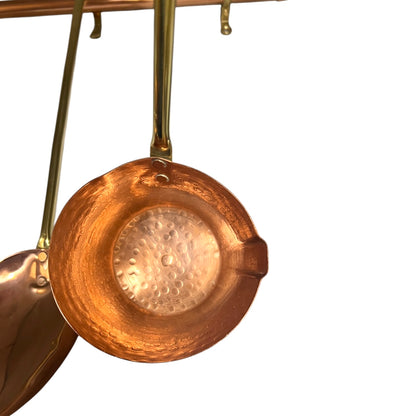 A copper ladle with a hammered interior and a brass hanging handle, shown against a plain white background.