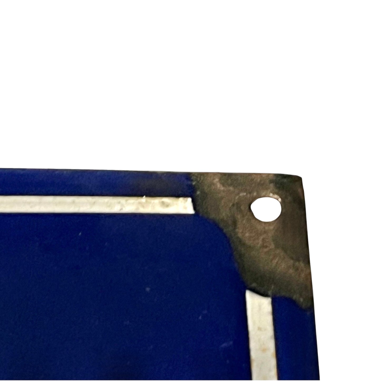 Close-up of the corner of a dark blue rectangular item with a metal bracket and a small circular hole, shown against a white background.