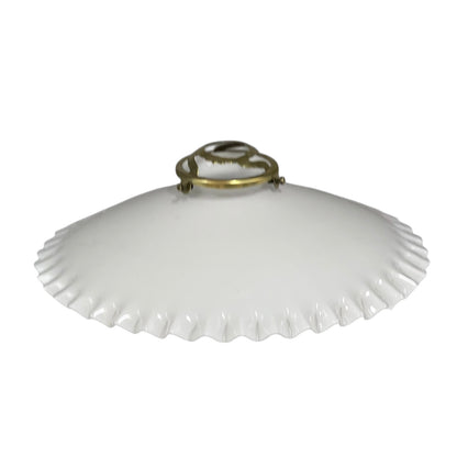 White lampshade with scalloped edge and brass fitting on a white background