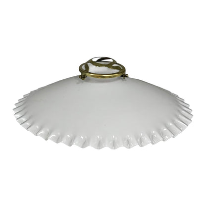 White scalloped-edge lampshade with brass fixture on a white background