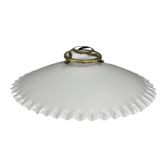 White scalloped-edge lampshade with brass fixture on a white background