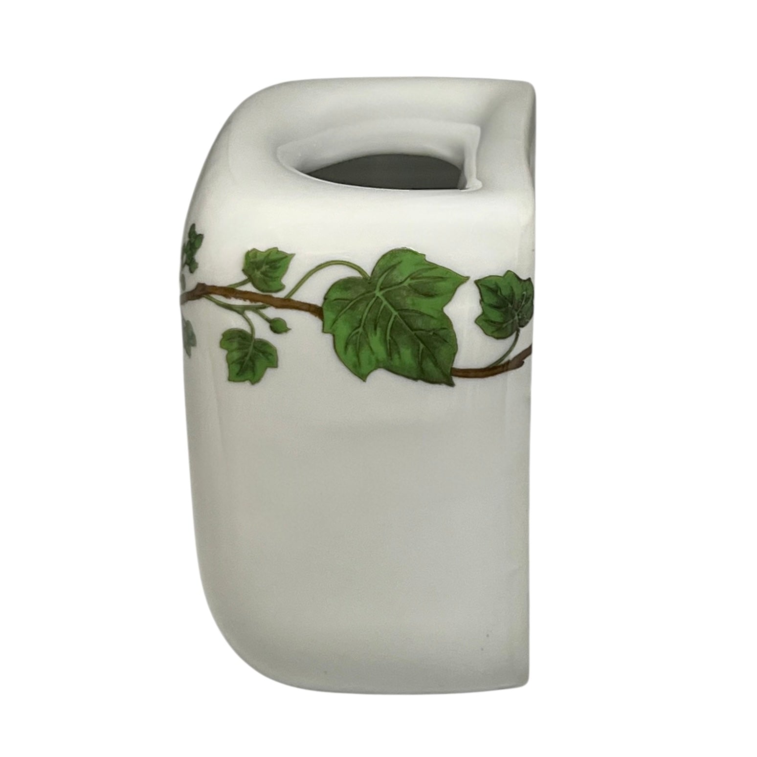 White ceramic toothbrush pot with green leaf design on a white background