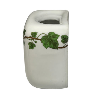 White ceramic toothbrush pot with green leaf design on a white background
