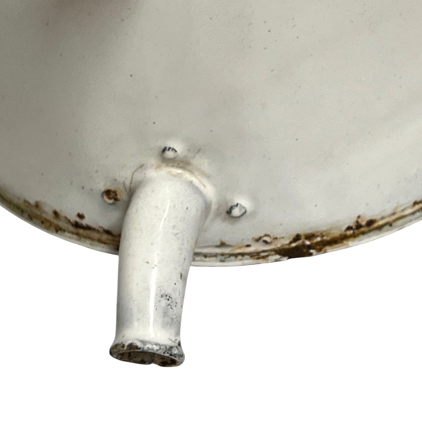 Close-up of the bottom interior of a white enamel or porcelain vessel with a protruding spout or handle, showing worn brown rust-like staining around the rim and base.