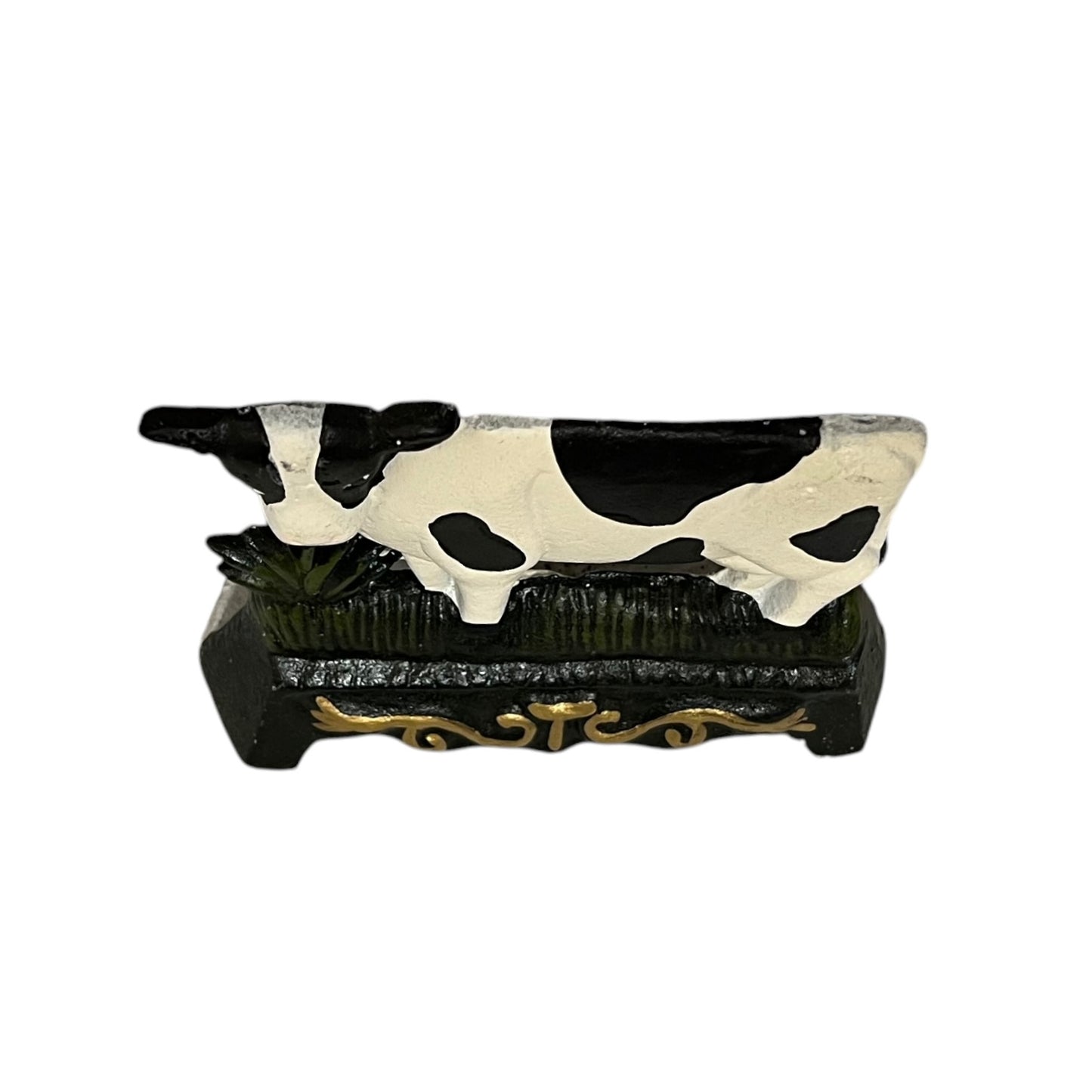Close up of small cow shaped cast iron doorstop on a white background