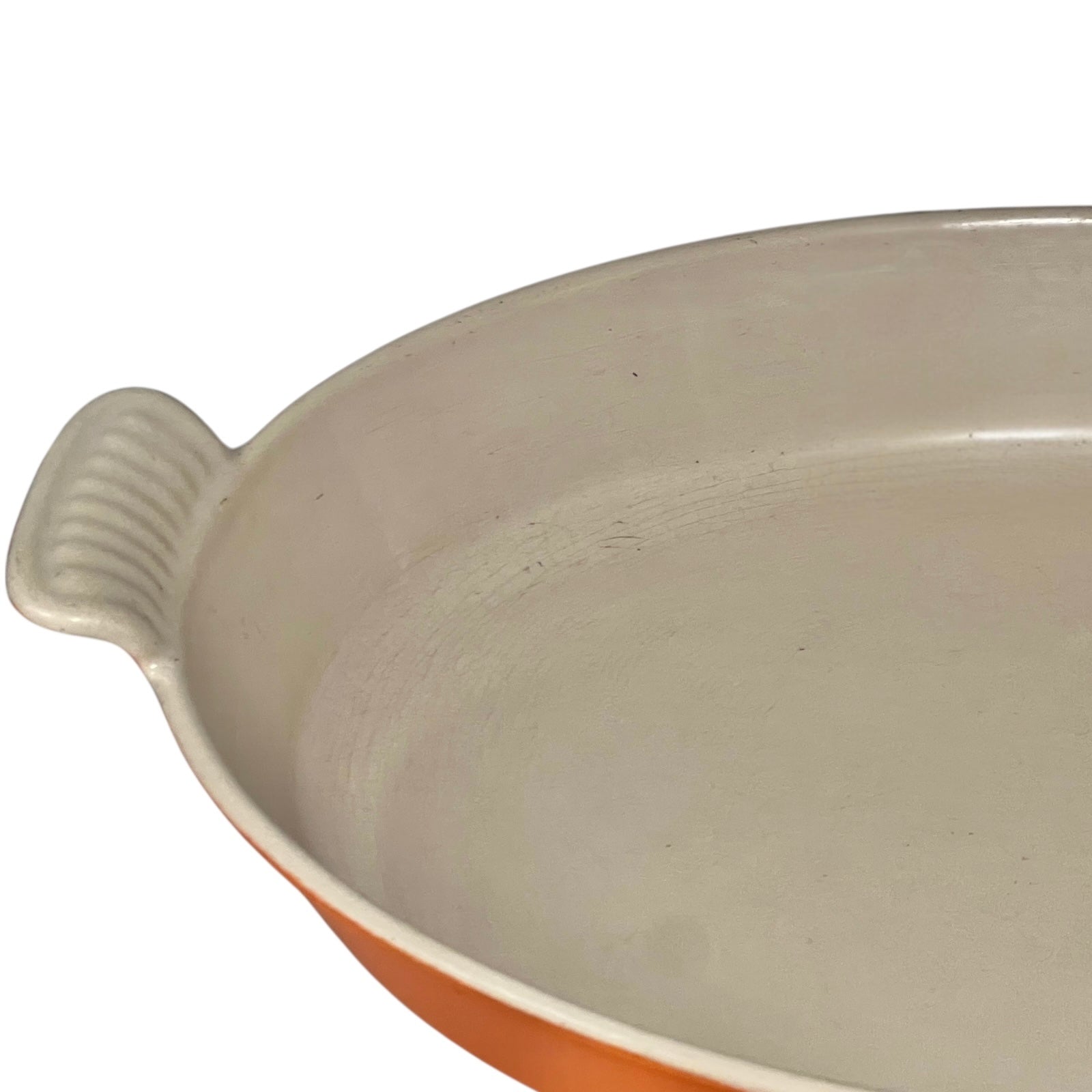 French orange Le Creuset dish with beige interior on a white background