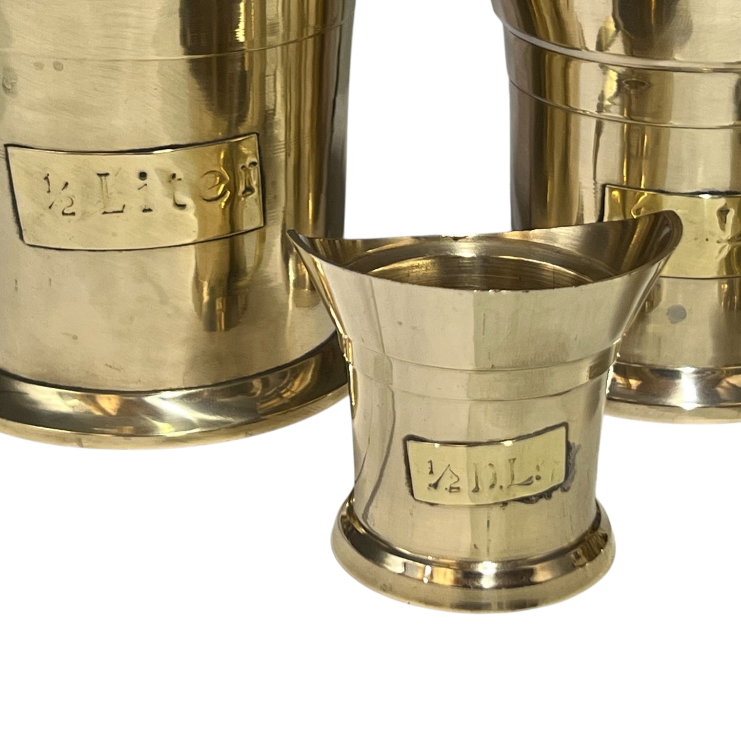 Brass measuring cups with measure sizes on a white background