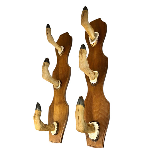 Two wooden wall hooks with deer hoof designs on a white background