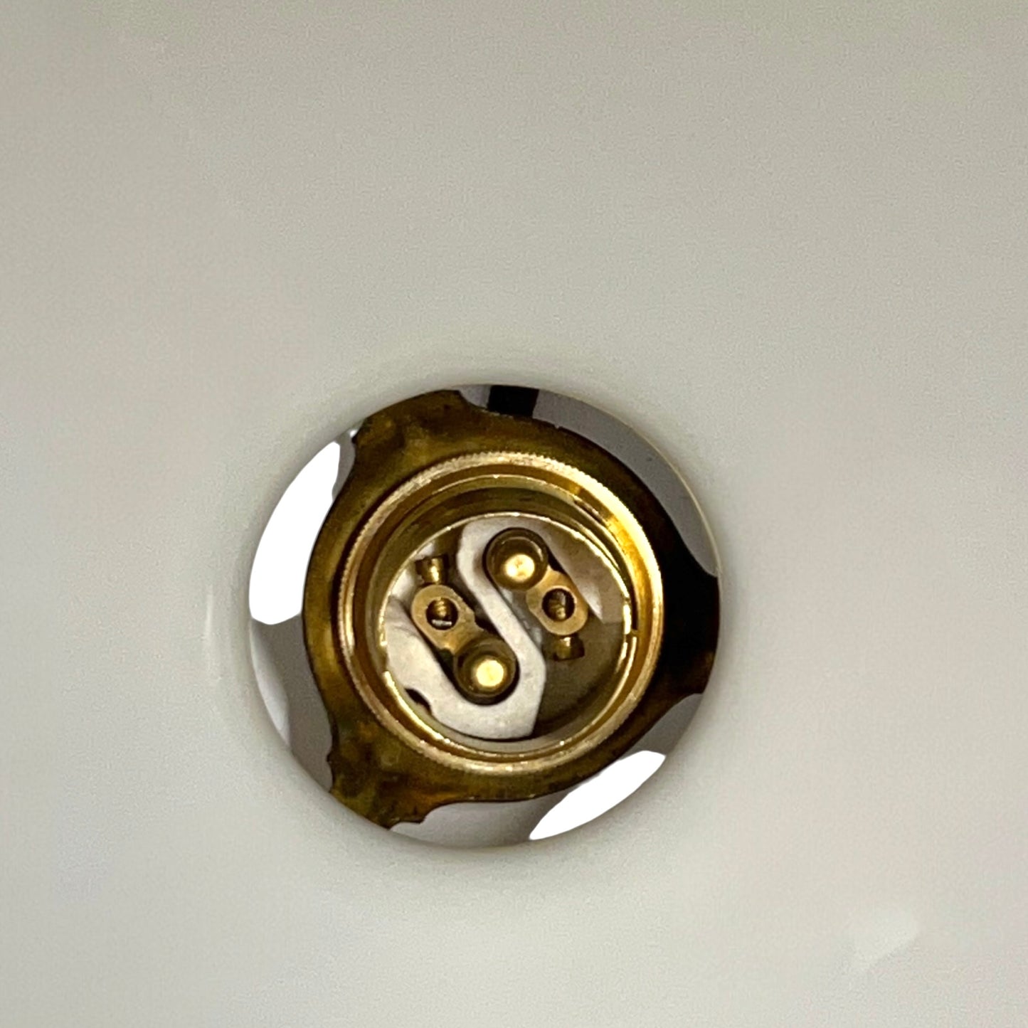 Close-up of a pendant light with white glass shade and brass fitting on a white background