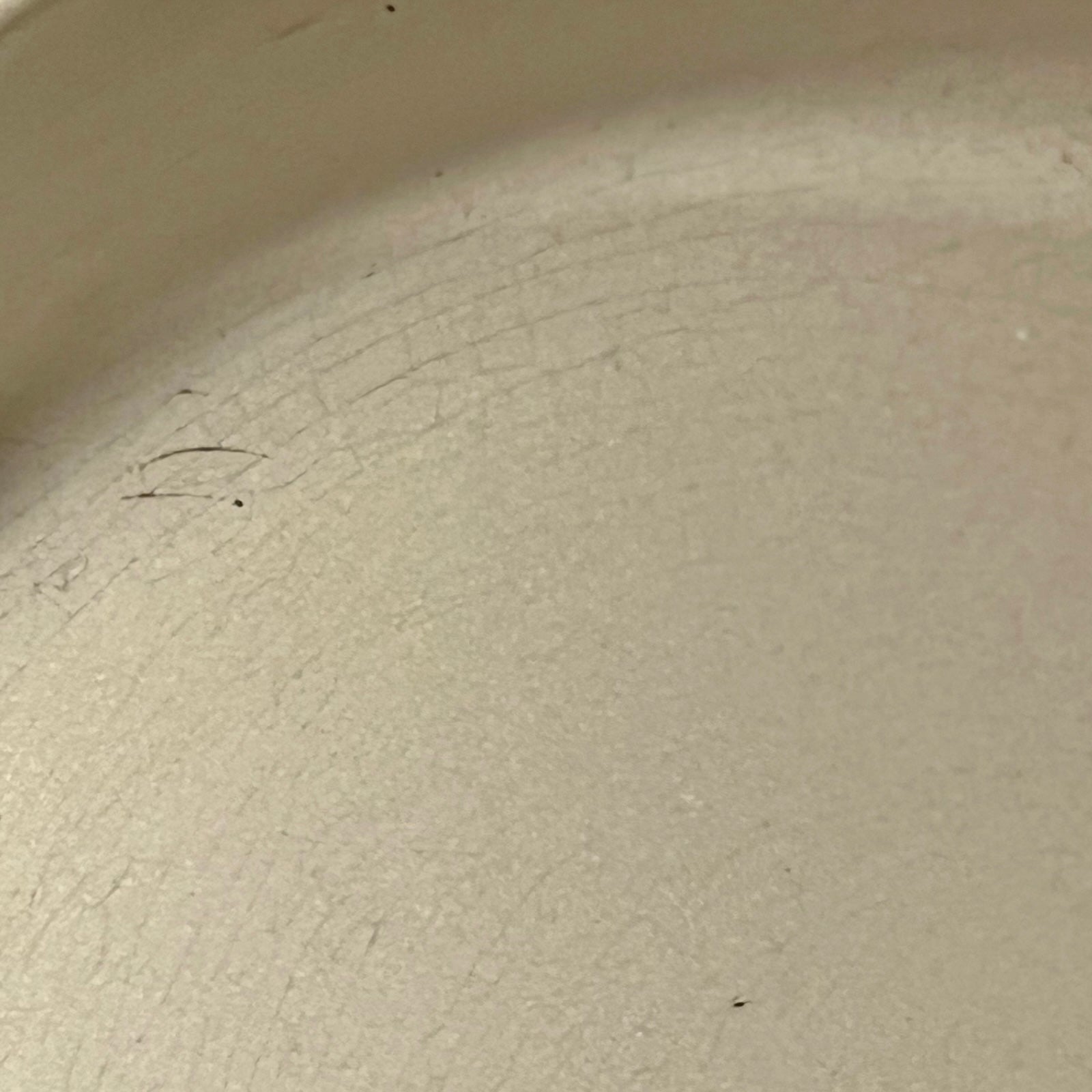 Close up of Le Creuset dish with beige interior on a white background