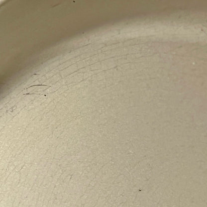 Close up of Le Creuset dish with beige interior on a white background
