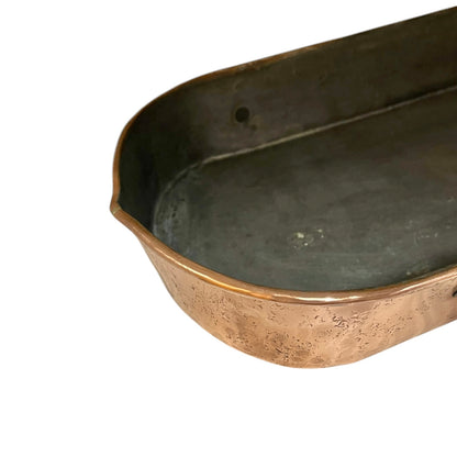 Close up of a copper roasting pan with a long handle on a white background