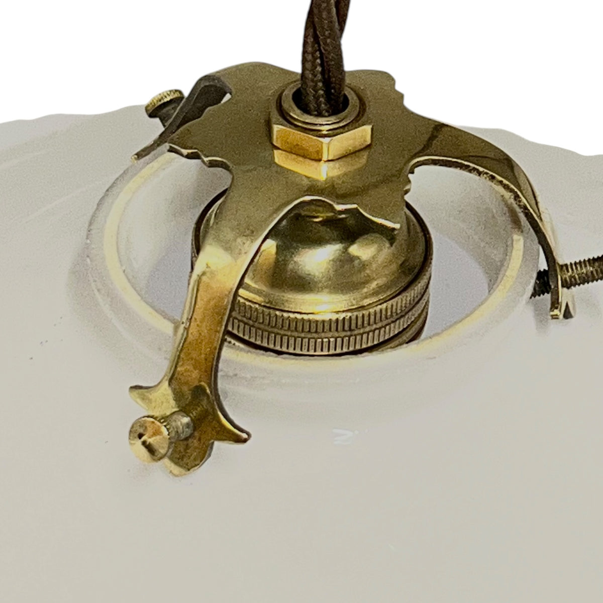 Close-up of a vintage brass ceiling mount fixture with a decorative star-shaped bracket and a brown hanging cord, attached to a white glass shade.