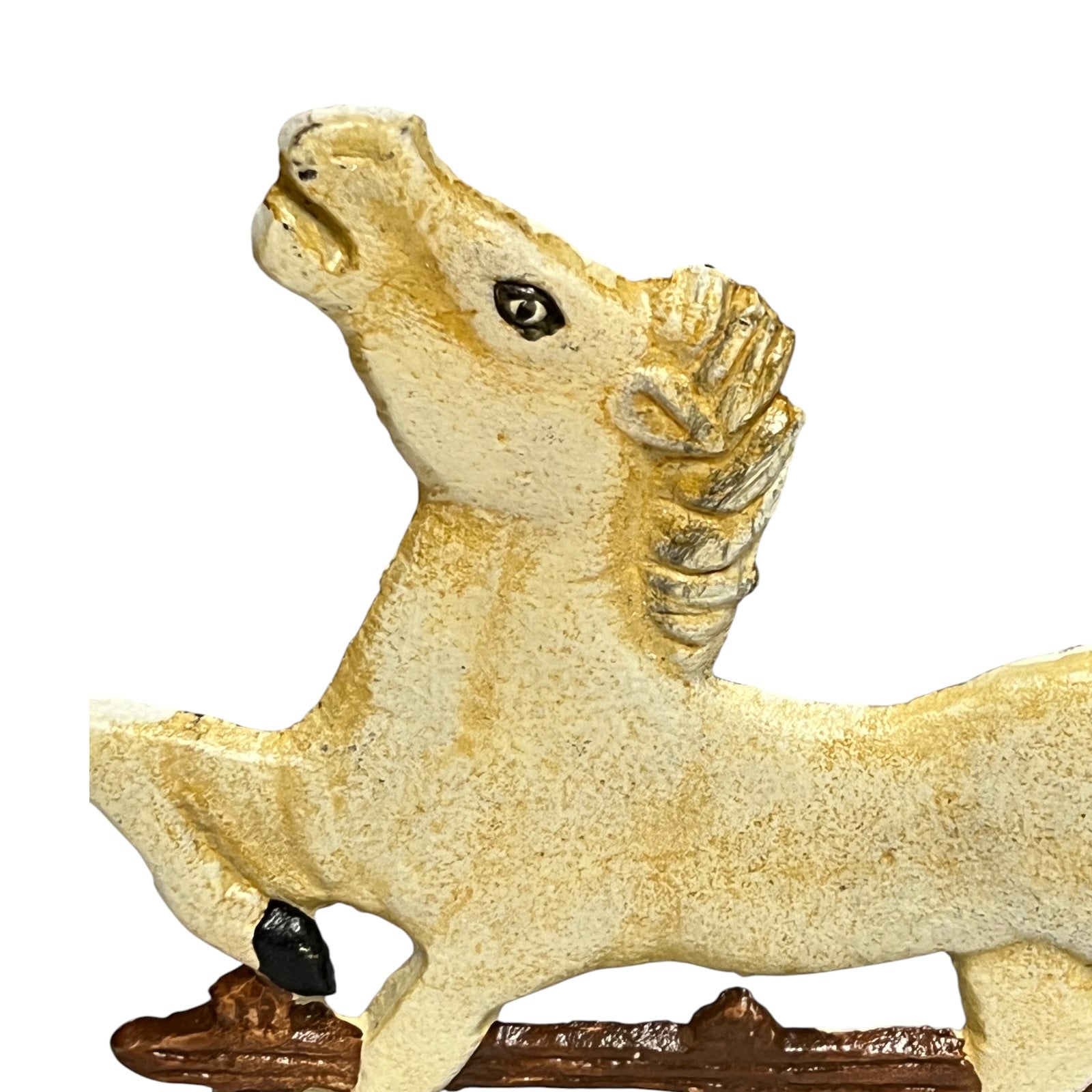 A close-up of a textured horse figurine in cream and gold tones with a small black hooves detail, set against a plain white background.