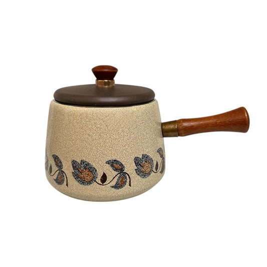 Retro saucepan pot with a beige speckled pattern and floral designs and wooden handle on a white background