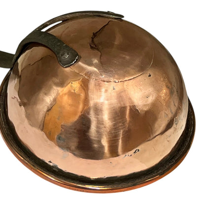 A vintage copper dome-shaped pot lid or cover with a dark metal handle, shown on a plain white background.