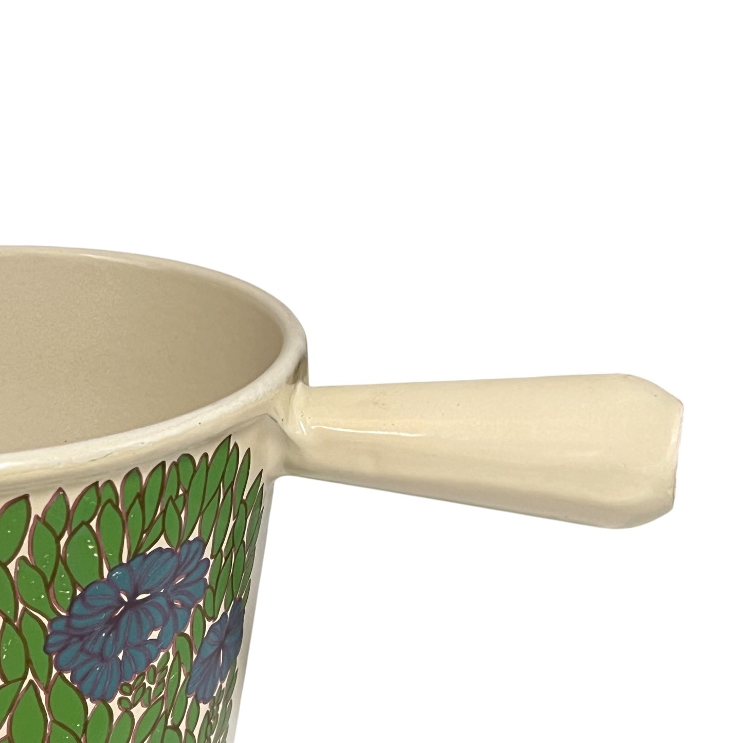 Vintage Le Creuset cast iron fondue pan in rare 1970s floral design, with blue flowers and green leaves, showing the handle styled on a white background 