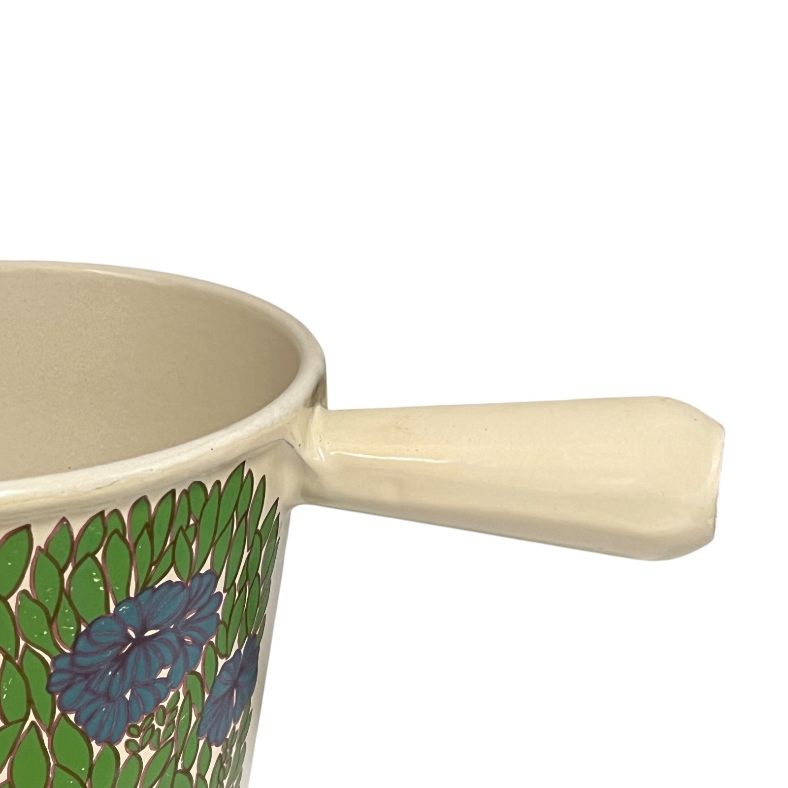 Vintage Le Creuset cast iron fondue pan in rare 1970s floral design, with blue flowers and green leaves, showing the handle styled on a white background 