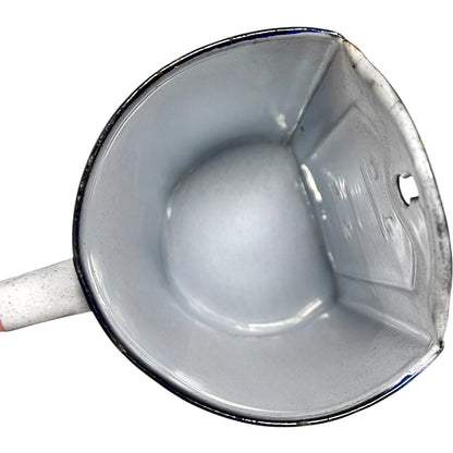 Close-up of the inside of an enamel planter with speckled glaze and blue rim on a white background