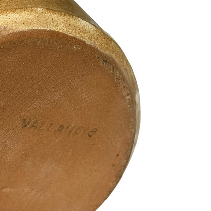 Close-up of the bottom edge of a terracotta-colored ceramic vessel, showing a stamped brand mark reading 'VALLANCE' on a plain white background.