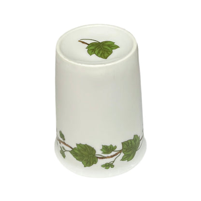 Porcelain bathroom tumbler  featuring green leaf patterns on a white background