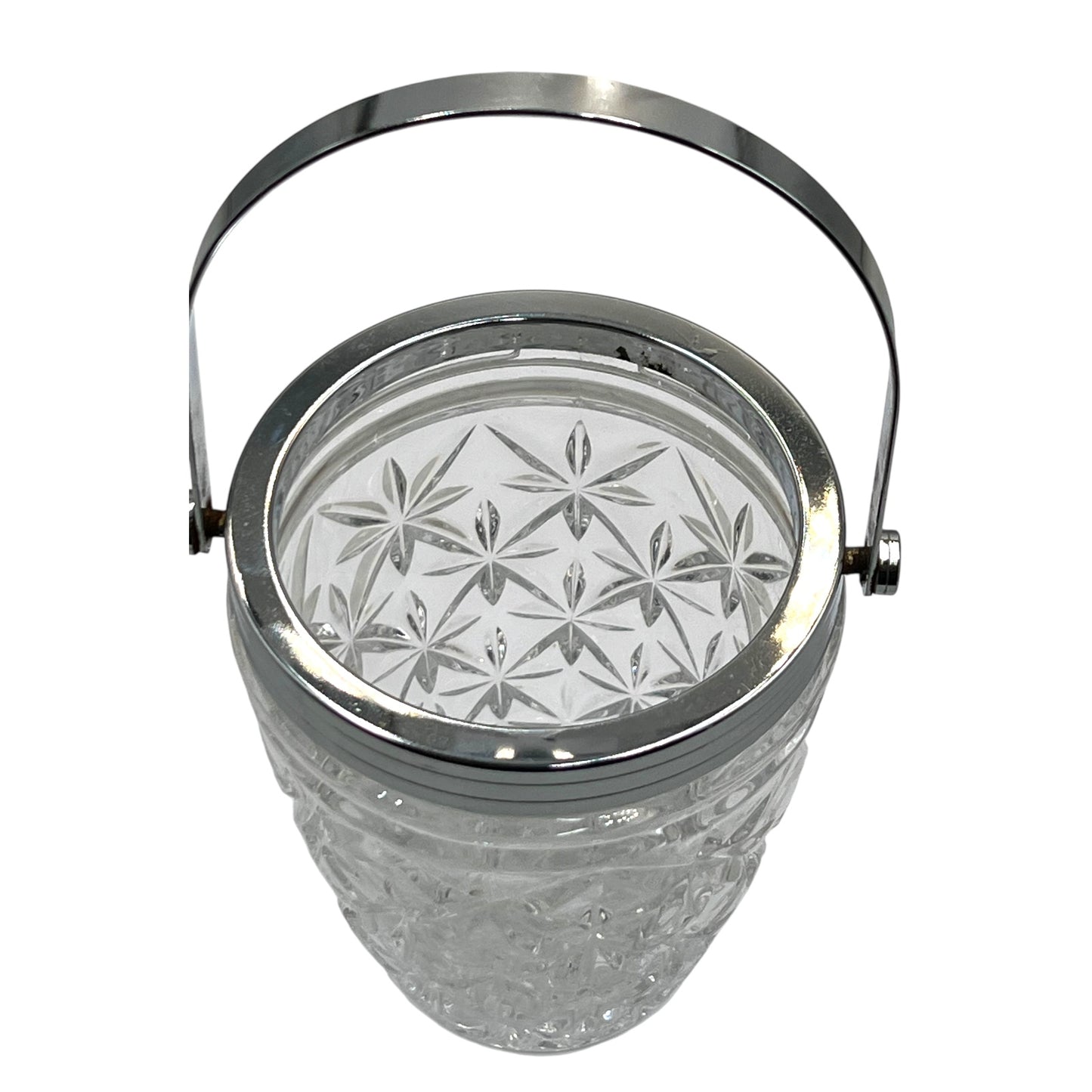 Clear French cut glass ice bucket with textured design and metal handle on a white background
