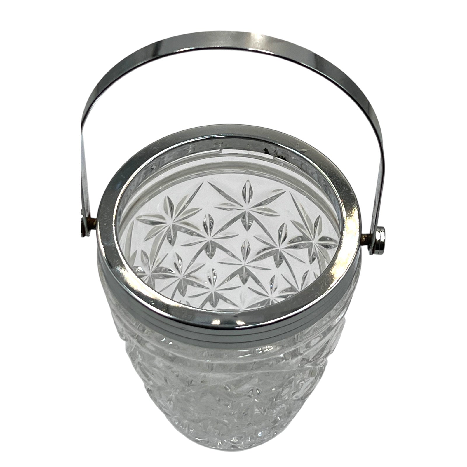 Clear French cut glass ice bucket with textured design and metal handle on a white background