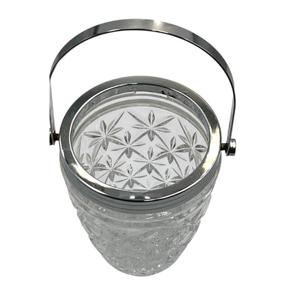 Clear French cut glass ice bucket with textured design and metal handle on a white background