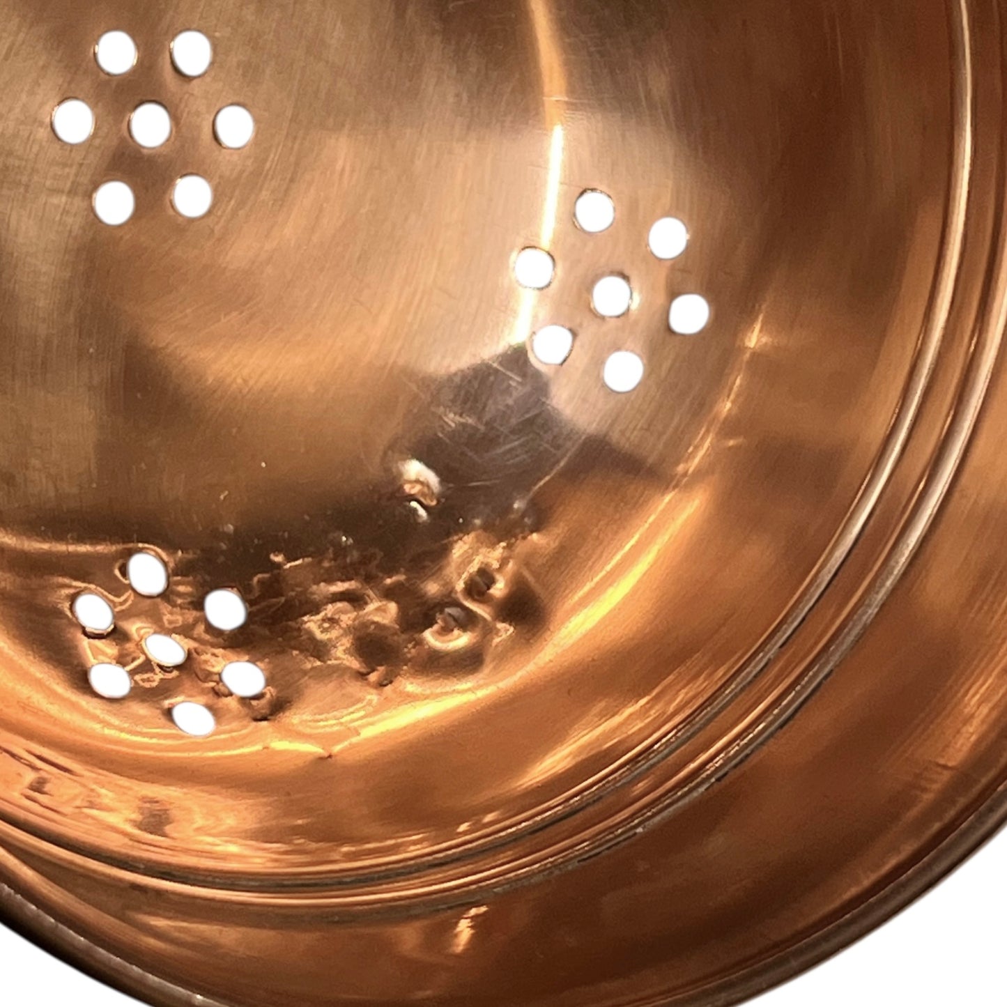 Close up of a small copper French sieve with a brass handle on a white background