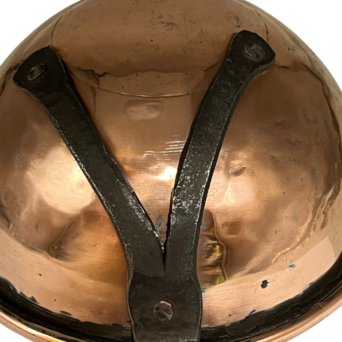 Close-up of a hammered copper bowl with a black metal Y-shaped support bracket attached to the inside rim, shown against a plain white background.