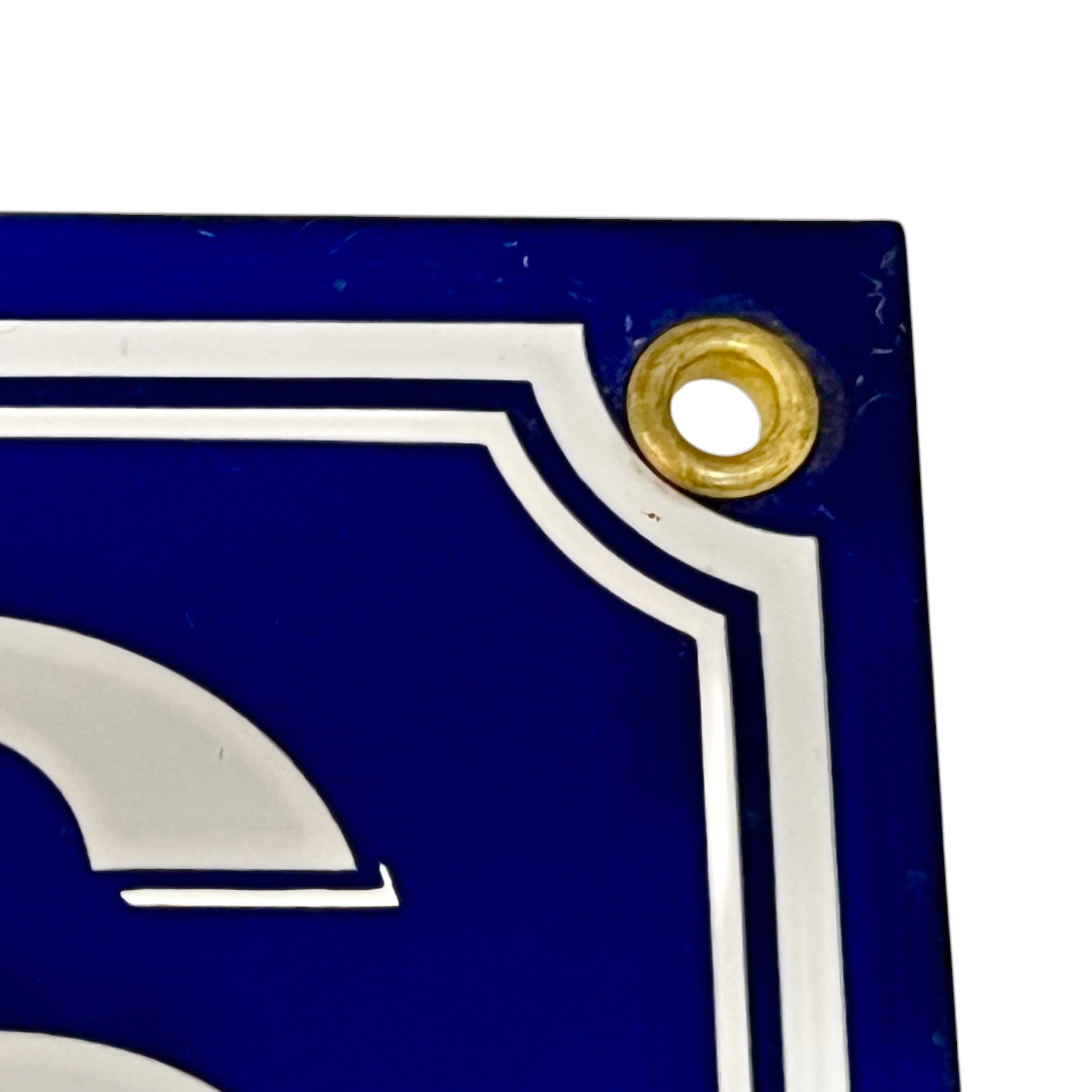 Close-up of a blue sign with white letter 'S' and gold accent on a white background