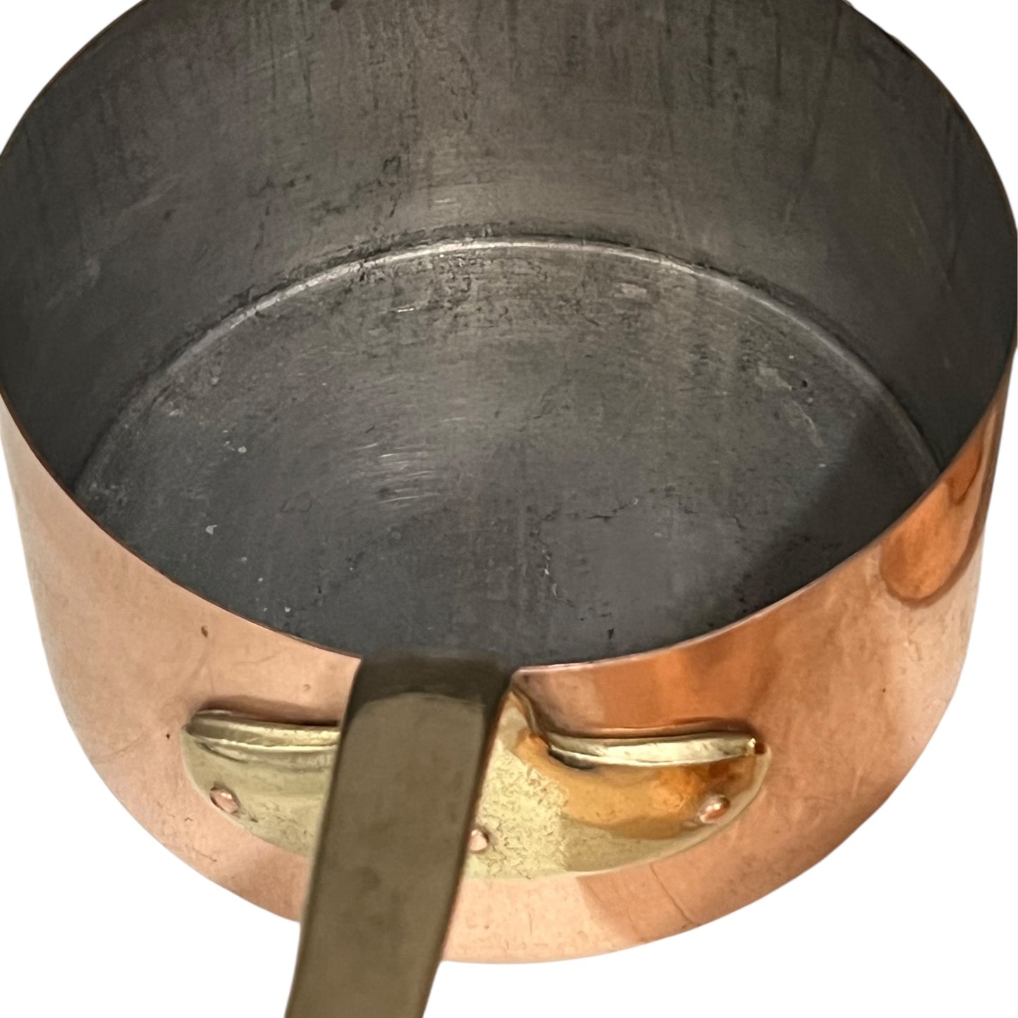 Close-up of a copper pot with a brass handle and tin lining on a white background