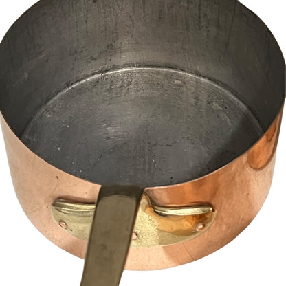 Close-up of a copper pot with a brass handle and tin lining on a white background