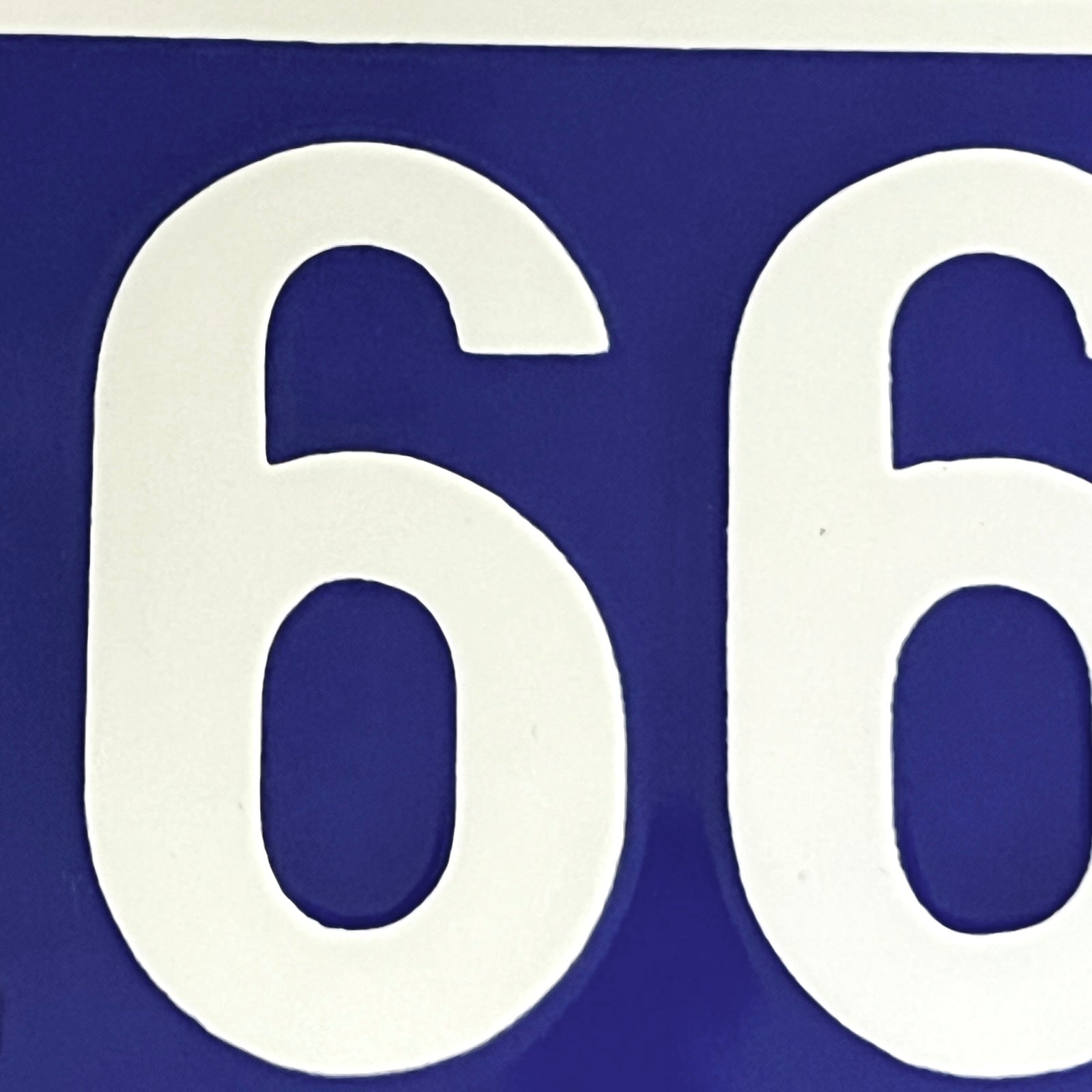 A close-up of a blue sign featuring large white numerals, showing the digits 6 and 6.