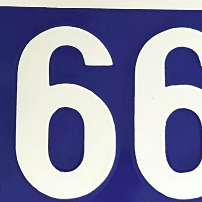 A close-up of a blue sign featuring large white numerals, showing the digits 6 and 6.