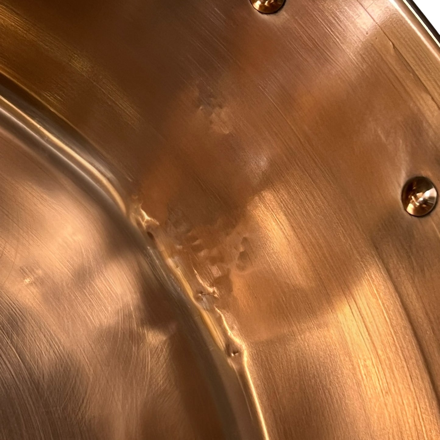 Close-up of a copper up cycled sink with brass handles on a white background.