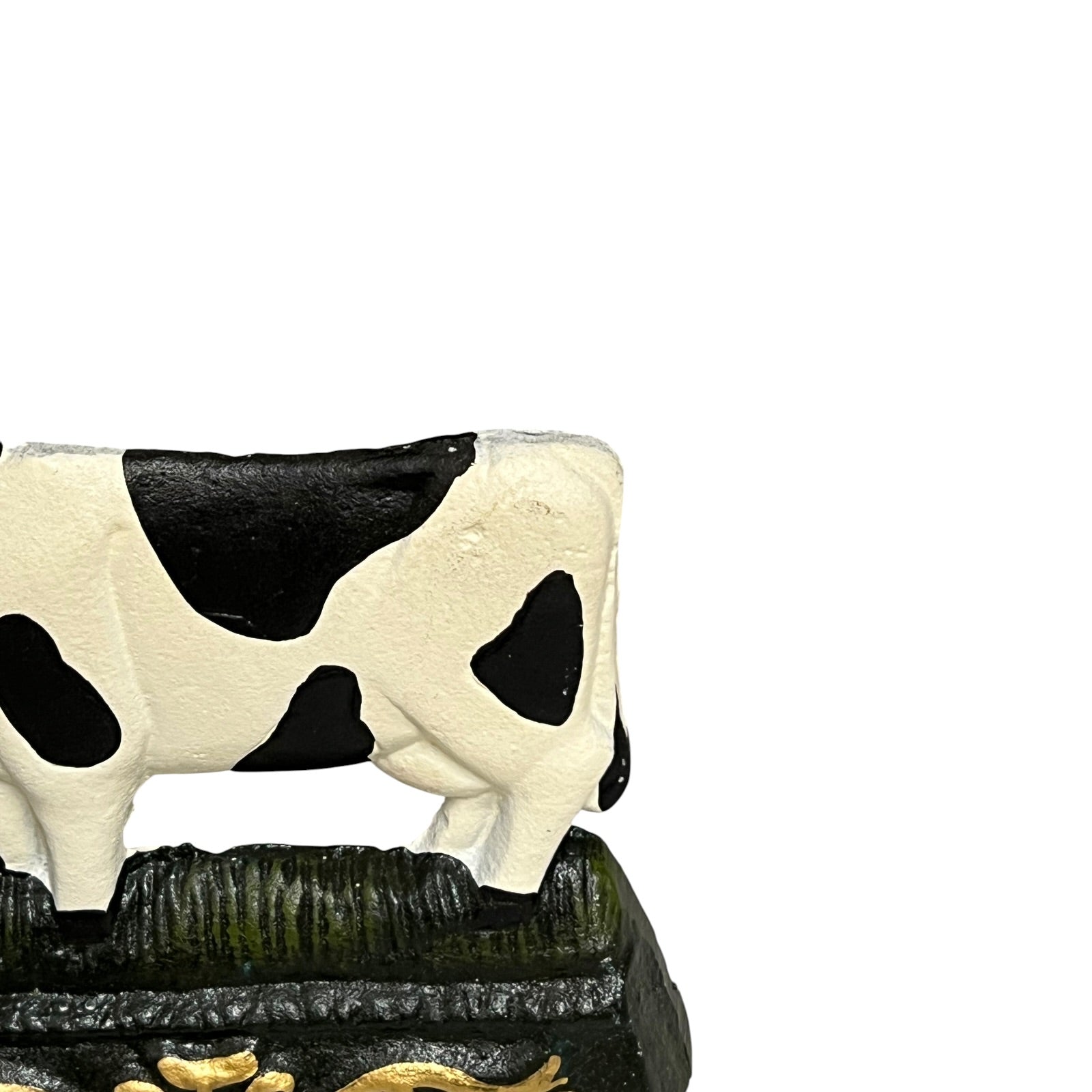 Close up of small cow shaped cast iron doorstop on a white background