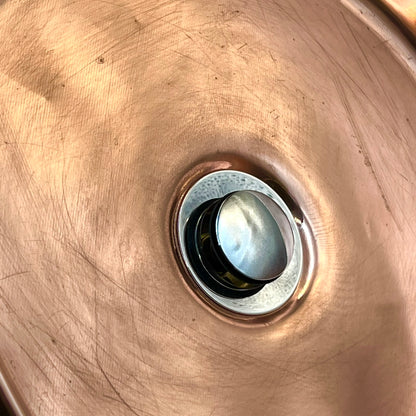 Close-up of a metallic object with a central circular component on a bronze surface.