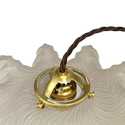 Close up of a glass lampshade and brass fittings on a white background
