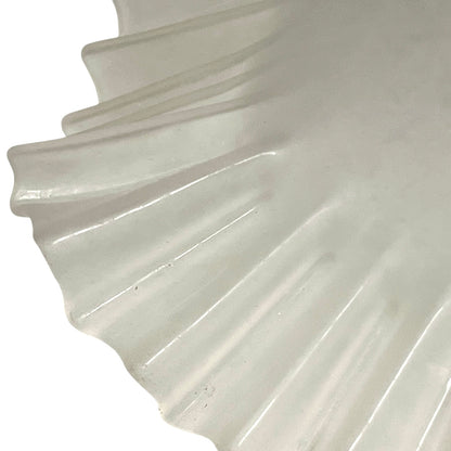 Close-up of a glass lamp shade with a scalloped edge on a white background