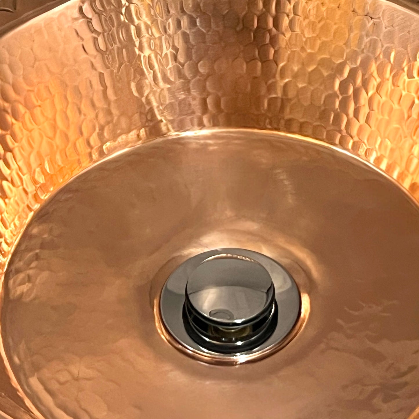 Close-up of a copper sink with a shiny drain.