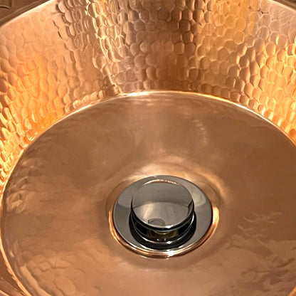 Close-up of a copper sink with a shiny drain.