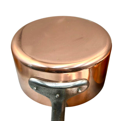 A close-up of a copper saucepan with a silver metal handle, shown against a plain white background.