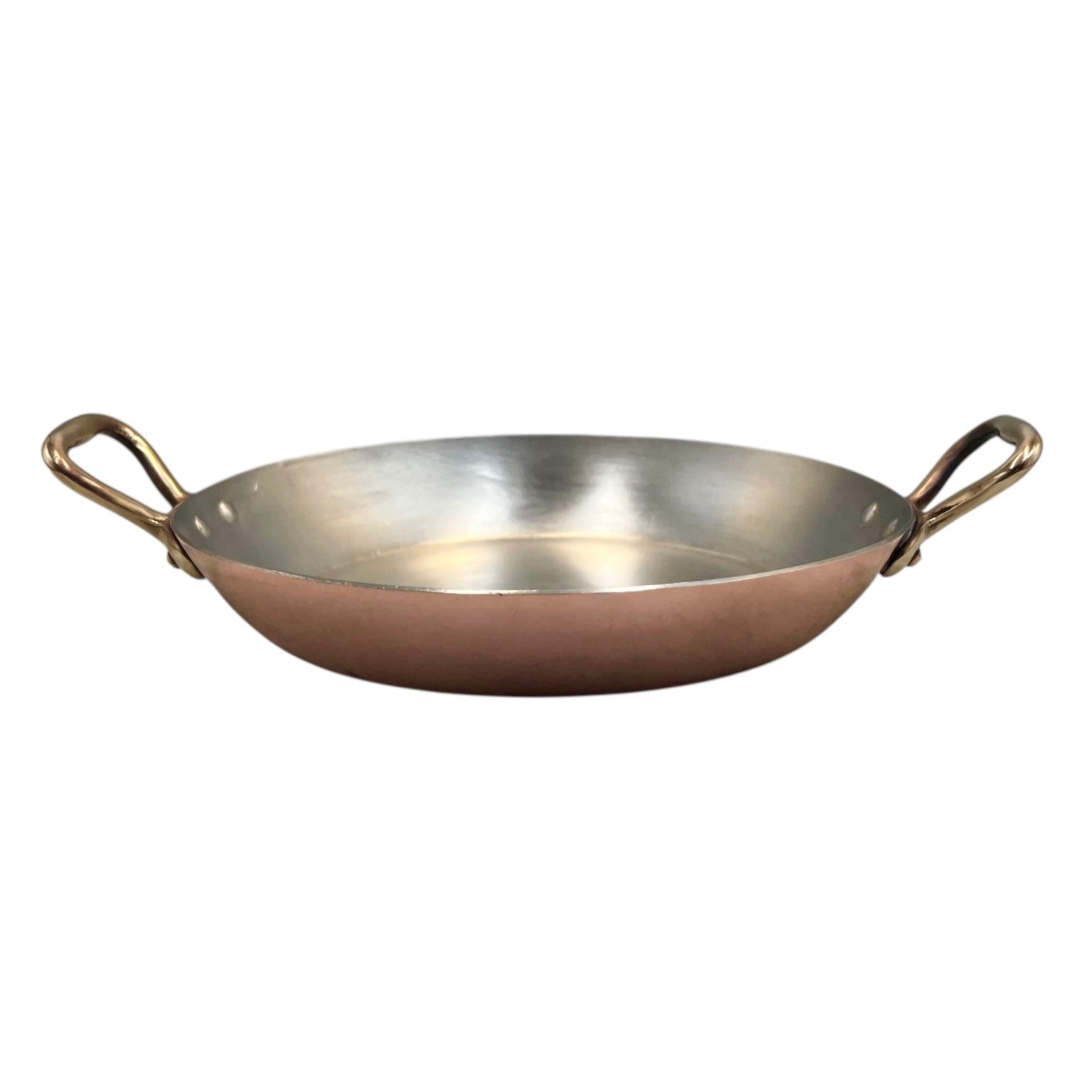 French copper round gratin pan with brass handles and tin lining on a white background