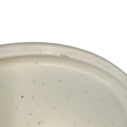 Close-up of a beige ceramic bowl with speckled texture on a white background