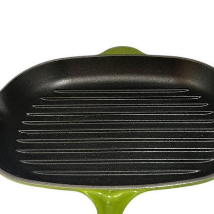 Green Le Creuset cast iron frying pan with black interior on a white background