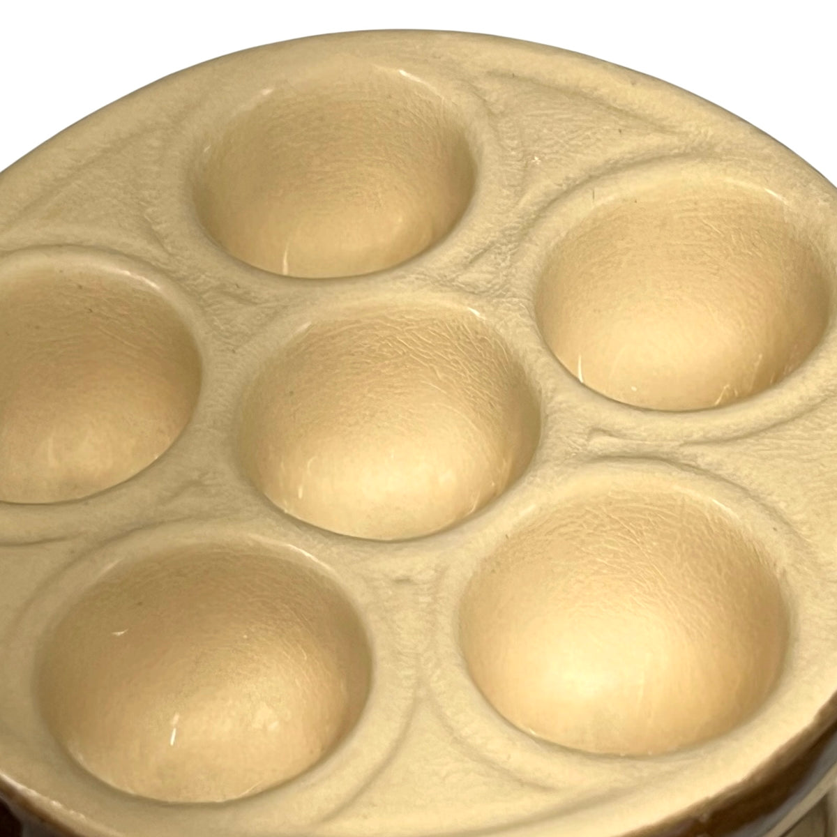A close-up of a beige escargot plate inner on a white background .