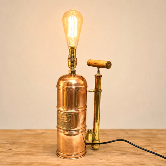 Copper and brass lamp with a lit bulb on a wooden surface ideal for a rustic country home 