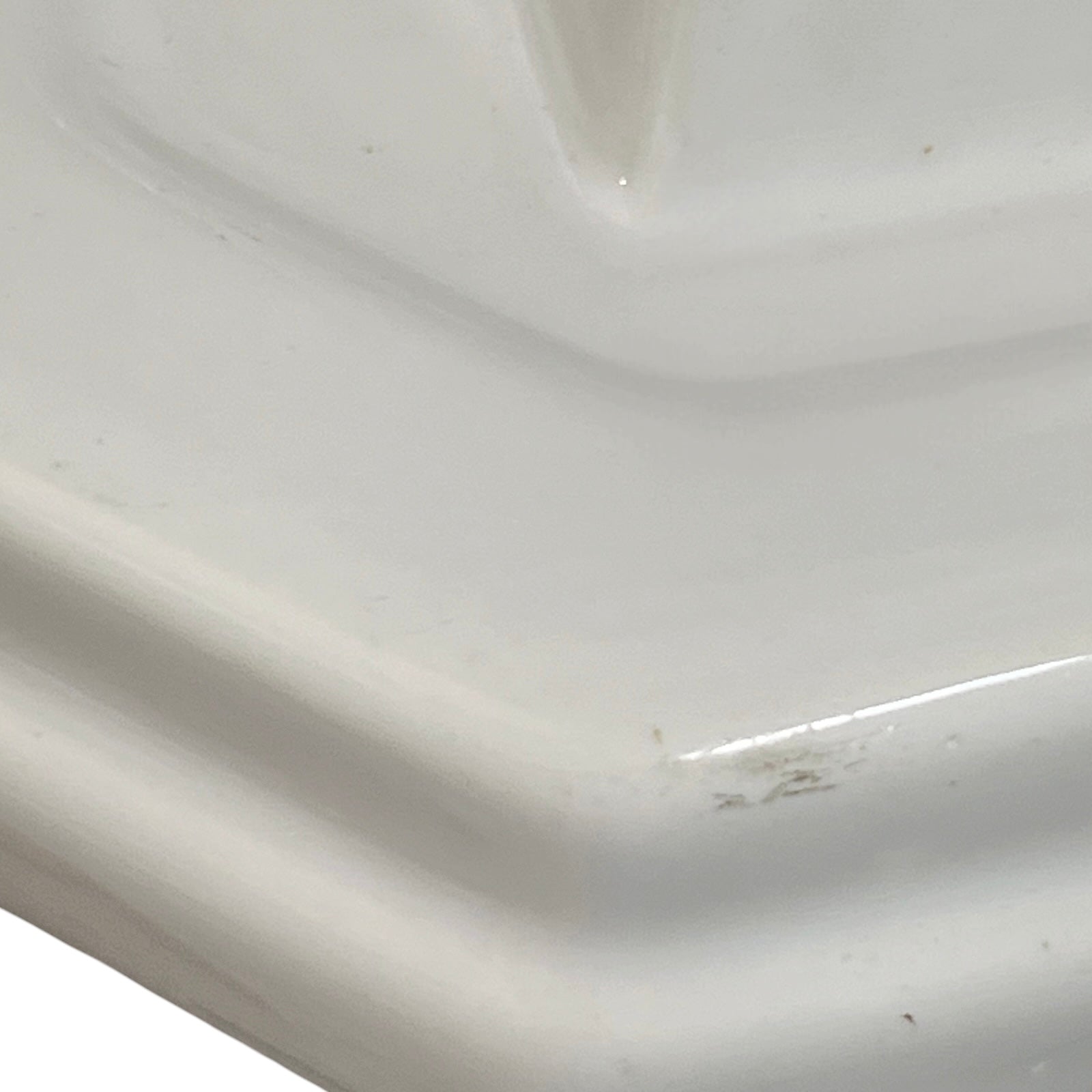Close-up of a white ceramic shelf with visible wear and tear.